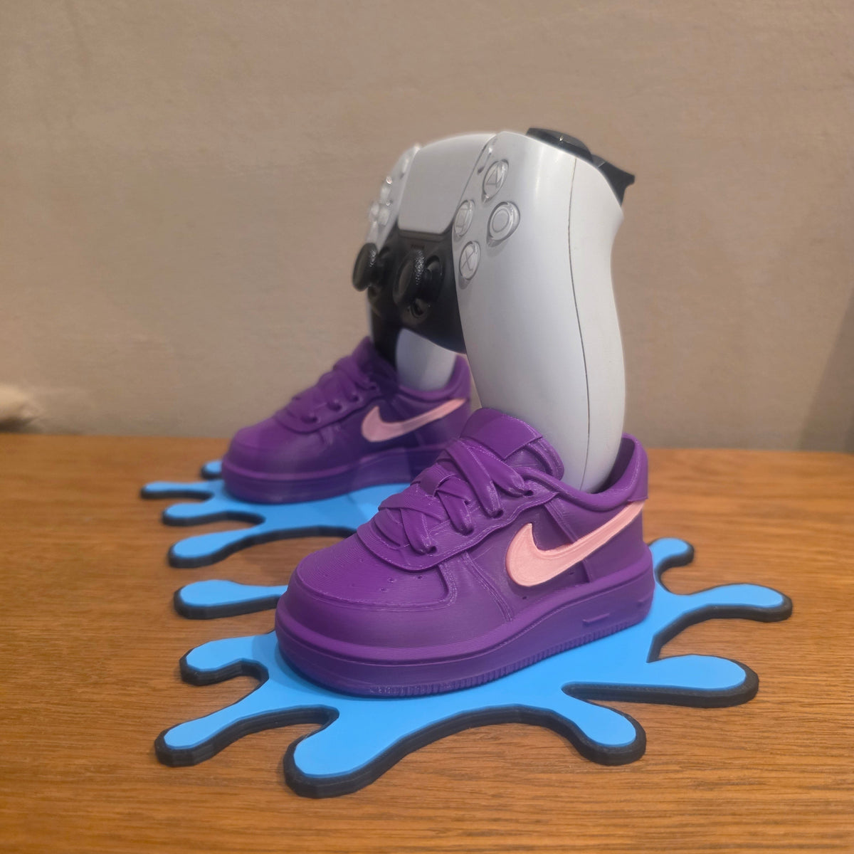 3DPrintingLabDesigns sneaker-inspired purple and pink PS5 controller stand on a blue paint splatter base