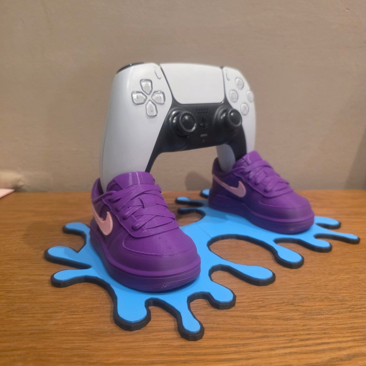 3DPrintingLabDesigns sneaker-inspired PS5 controller stand with purple shoes and a blue paint splatter base