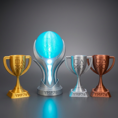 3D-printed PlayStation-style trophy set with an illuminated blue platinum trophy lamp and gold, silver and bronze cups on a charcoal studio background