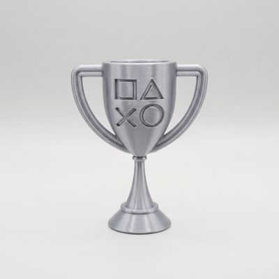 Silver 3D-printed PlayStation-style cup trophy with controller symbols on a light gray background
