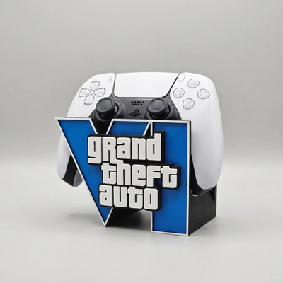 A white and black PlayStation 5 controller displayed upright on a custom blue and black stand featuring the Grand Theft Auto logo.