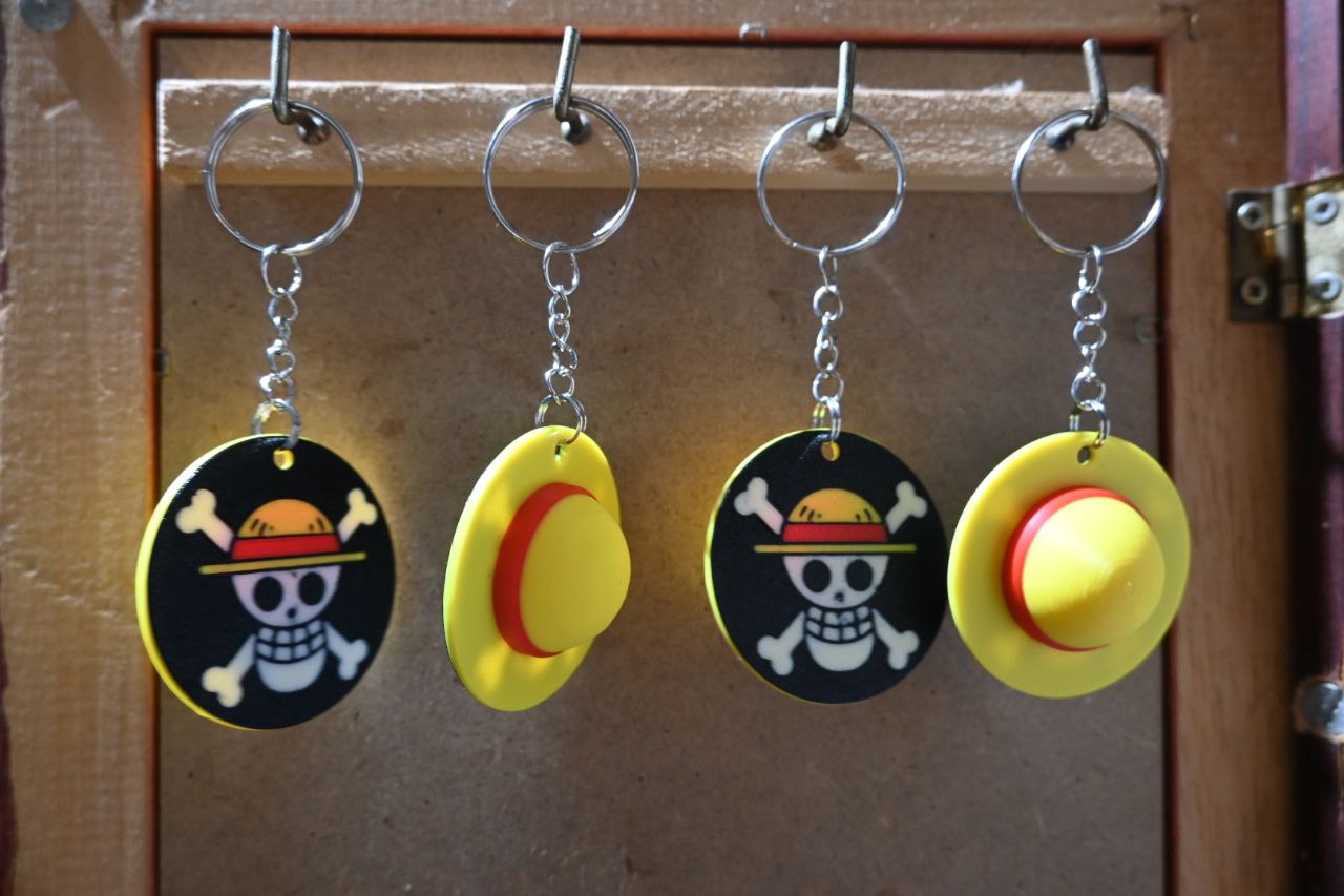 Four Straw Hat and Jolly Roger keychains hanging in a row, each showing the iconic yellow hat on one side and the skull emblem on the other.